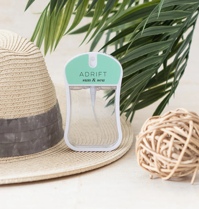 Product packaging labeled 'Adrift sun & sea' with a straw hat and decorative ball in the background.