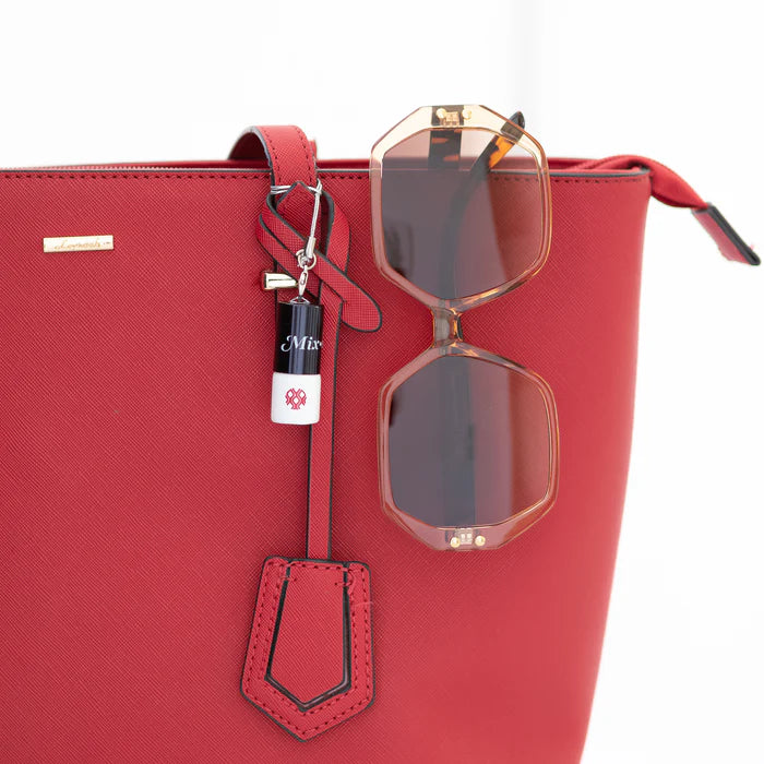 Red handbag with sunglasses and keychain on a white background