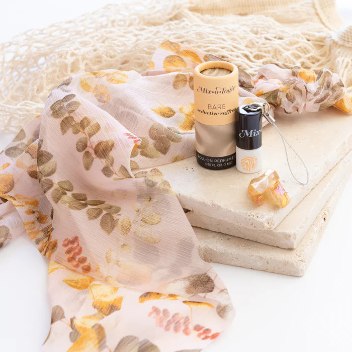 Two perfume bottles on a stone surface with a floral scarf in the background