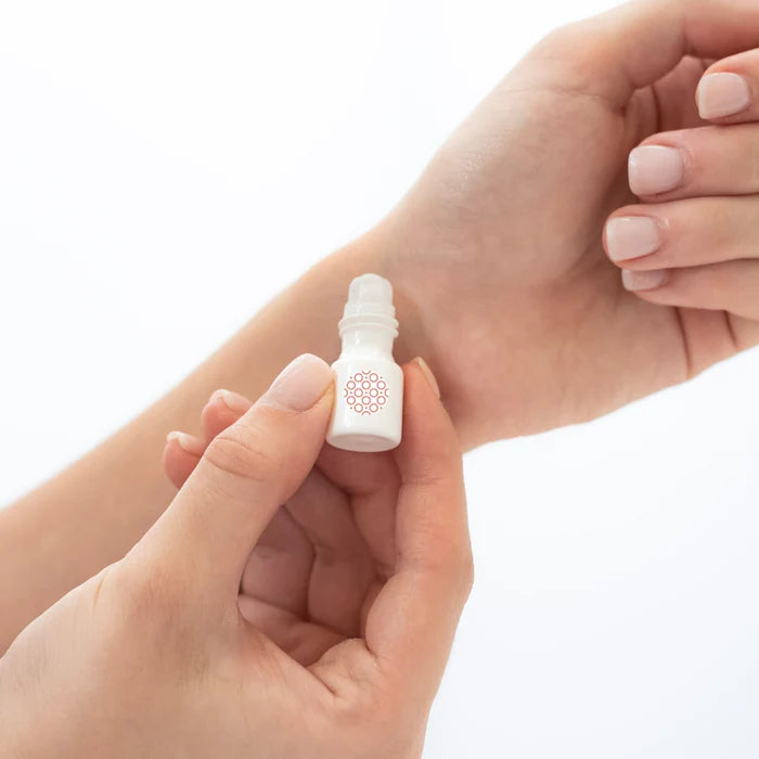 Small white bottle with a pink cap held between two hands against a light background