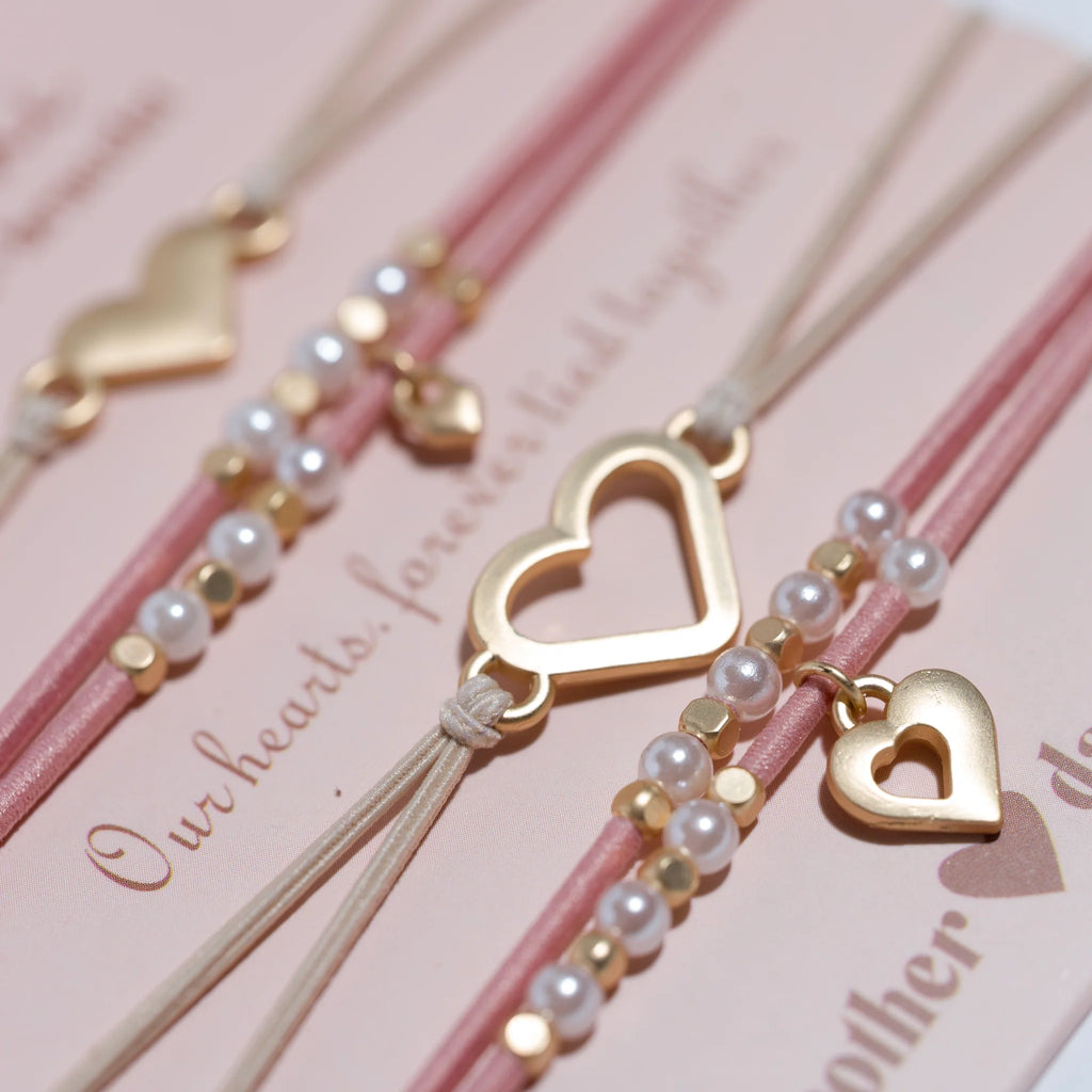 Bracelets with heart-shaped charms and pearl beads on a pink background