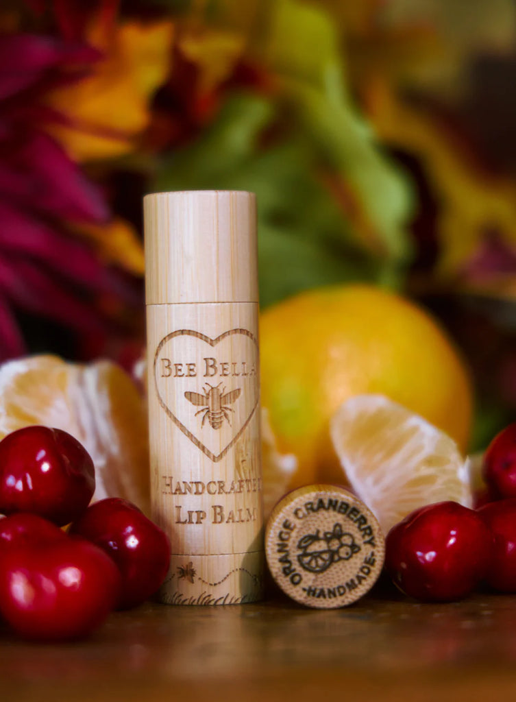 Bee Bella lip balm with cherry and orange background