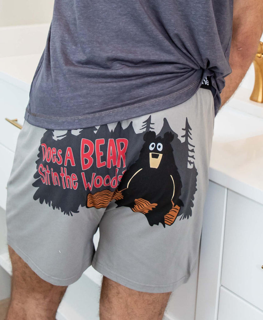 Person wearing gray shorts with a bear graphic and text in a kitchen setting