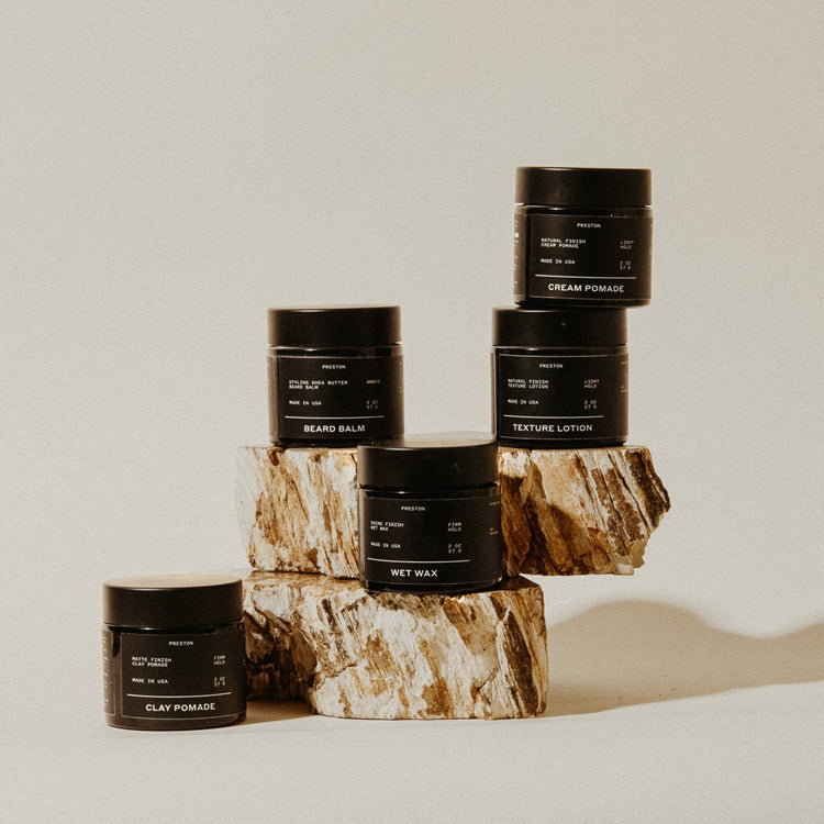 Set of black containers with labels on a wooden block against a neutral background