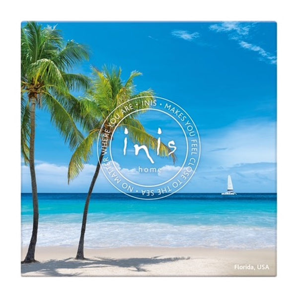 Canvas print of a tropical beach scene with palm trees and a sailboat, featuring the 'inis' brand.