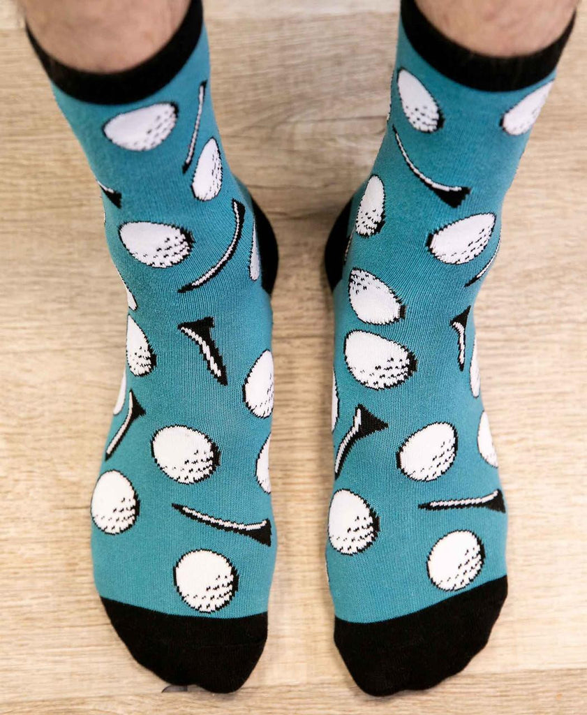 Teal socks with golf ball and club pattern worn on a wooden floor