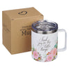 Stainless steel travel mug with floral design and text, next to a cardboard box