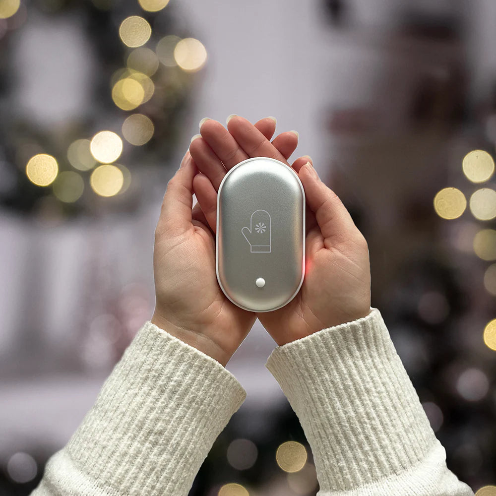 Hand holding a small electronic device with a blurred festive background