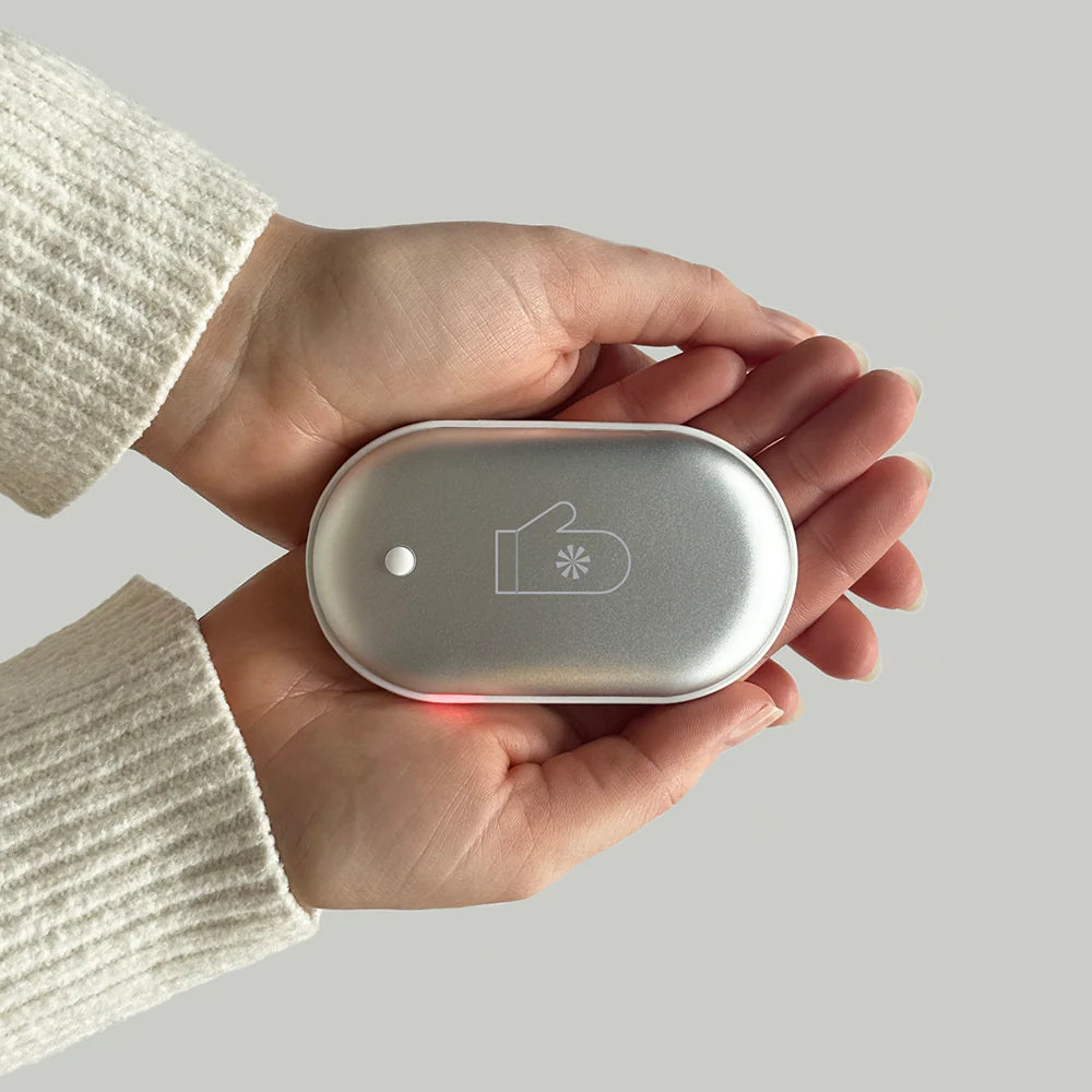 Hand holding a small electronic device with a minimalist design on a plain background