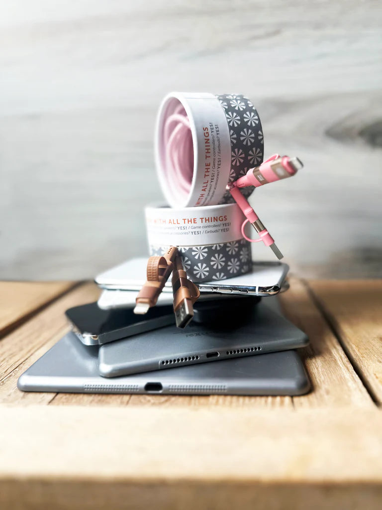 Stack of tablets with a smartphone on top, featuring decorative tape and scissors on a wooden surface.