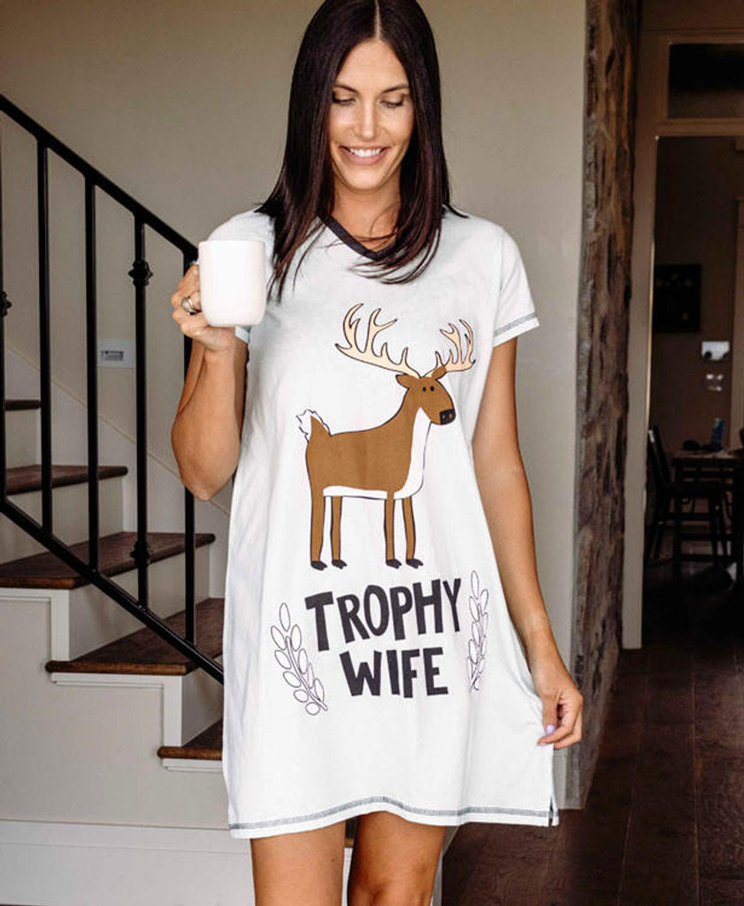 Woman wearing a white t-shirt with a deer graphic and 'Trophy Wife' text, holding a mug.