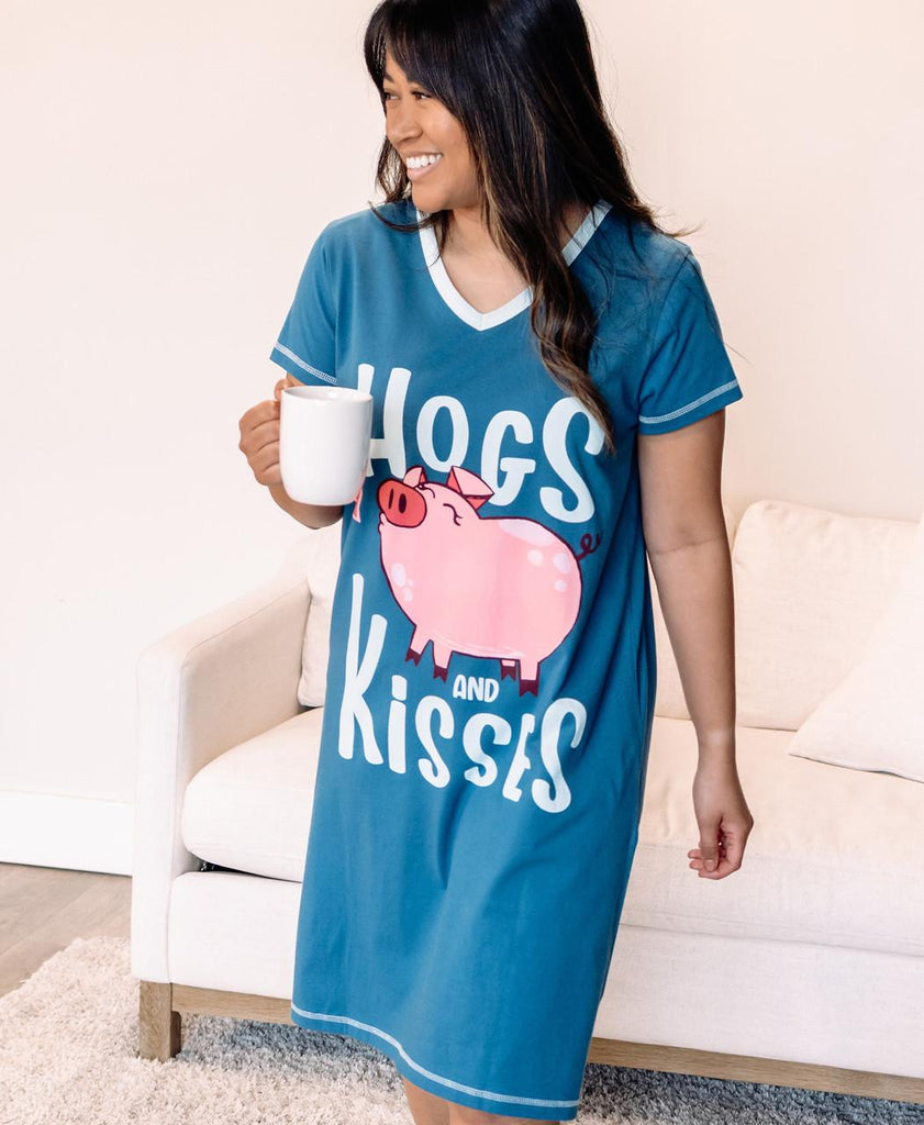 Woman wearing a blue nightshirt with a pig graphic and text, holding a mug.