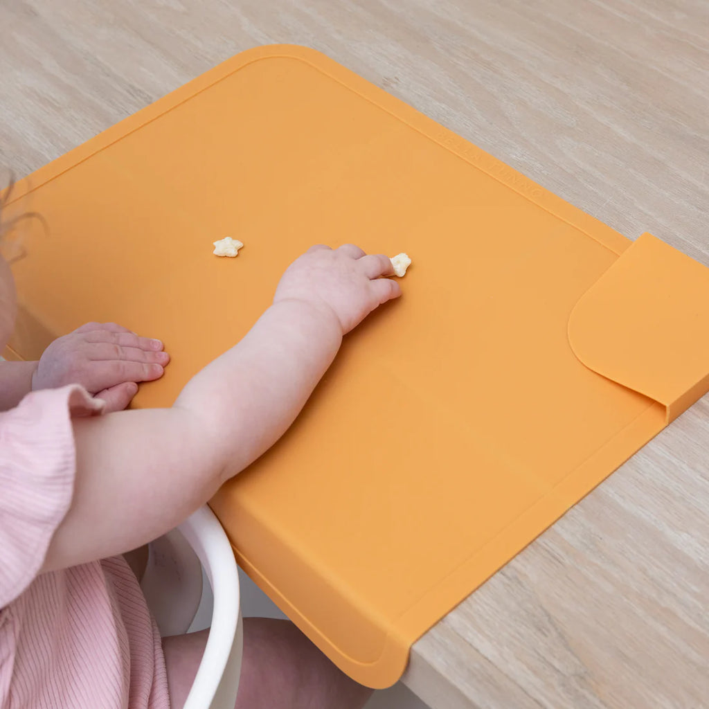 Baby's hand and foot on an orange mat with star-shaped objects