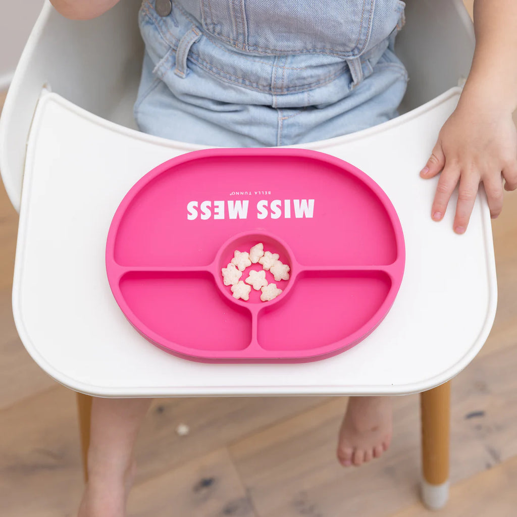 Pink children's tray with 'MISS MESS' text on a high chair