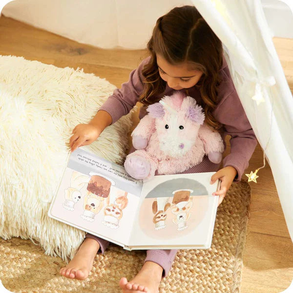 Child reading a book with a plush toy in a cozy indoor setting