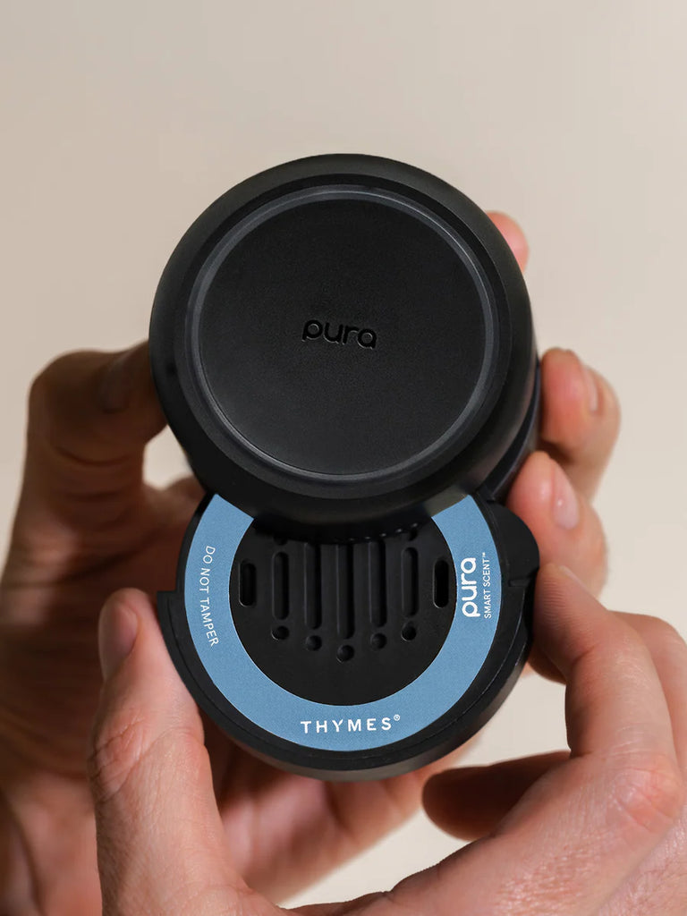 Black and blue diffuser with 'Thymes' branding held by a hand against a beige background