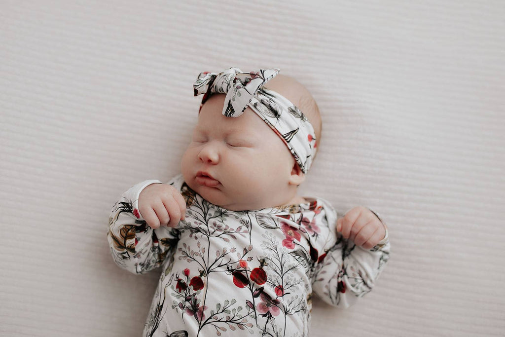 floral gown on a baby laying on a white background