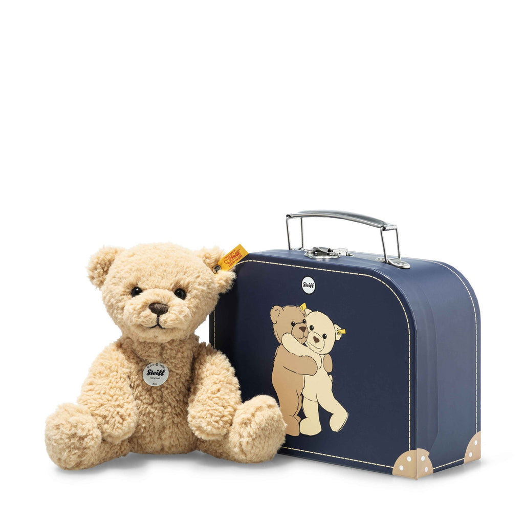 steiff brown bear with blue suitcase on a white background