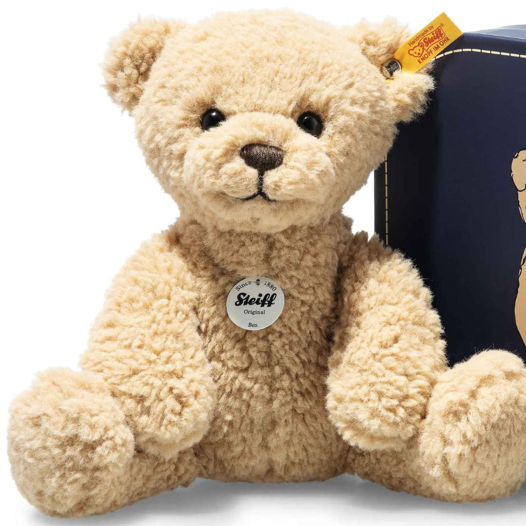 steiff brown bear with blue suitcase on a white background