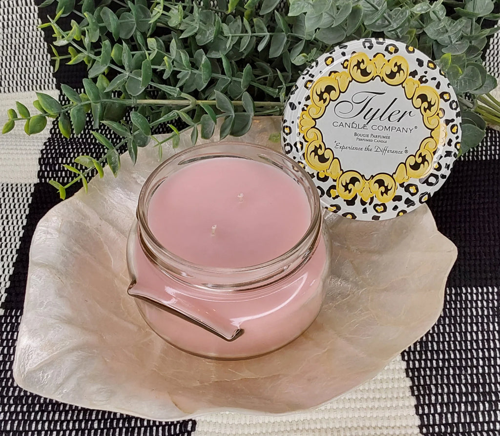 pink candle on a white platter with a green plant in the back