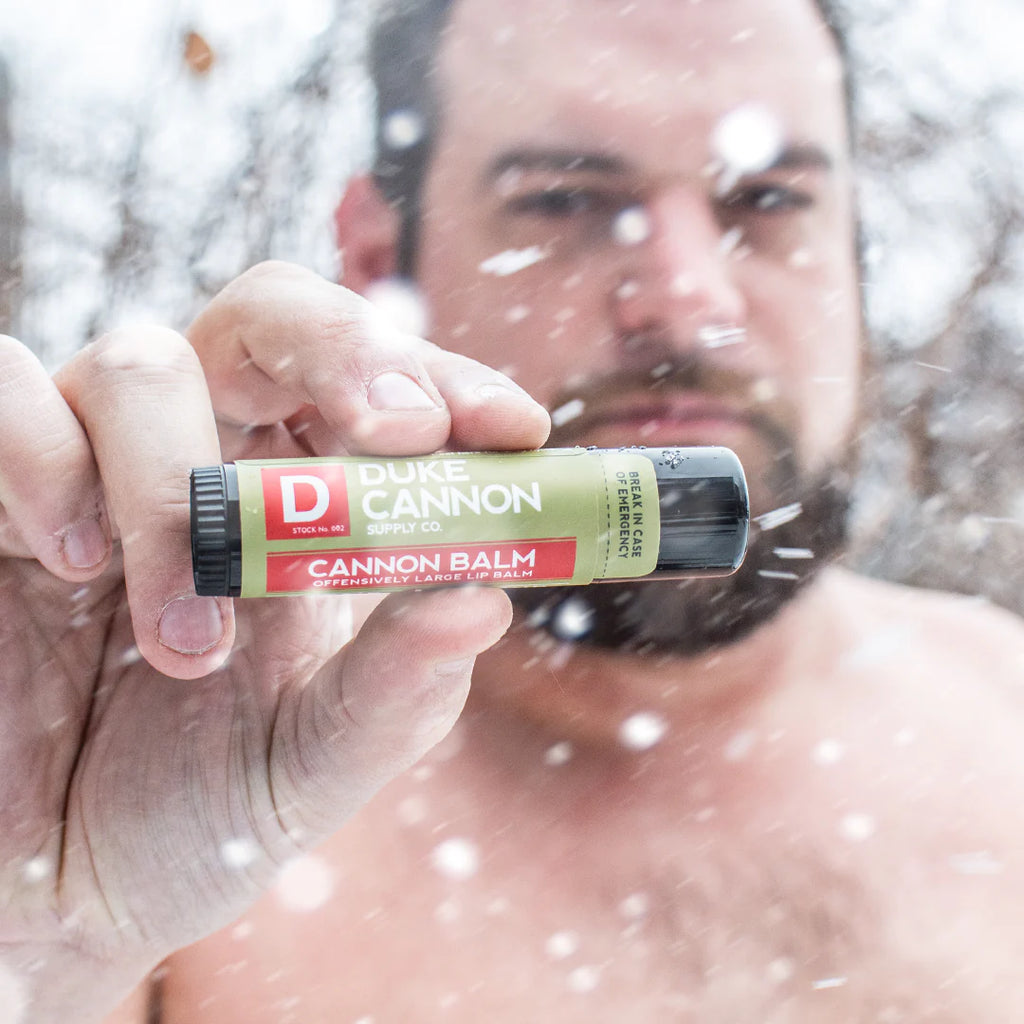 duke cannon lip balm being held by a man in the snow