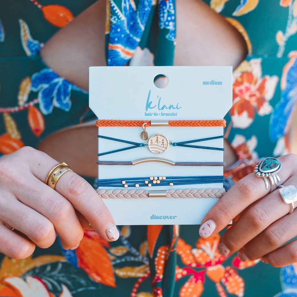 K' lime hair tie packaging held by a person with floral background