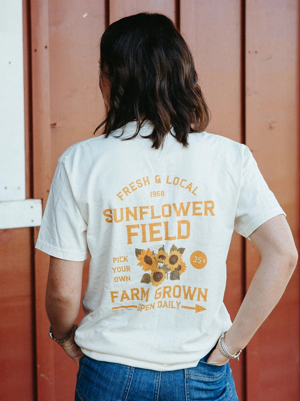 Person wearing a white t-shirt with 'Sunflower Field' text and sunflower graphics on the back.