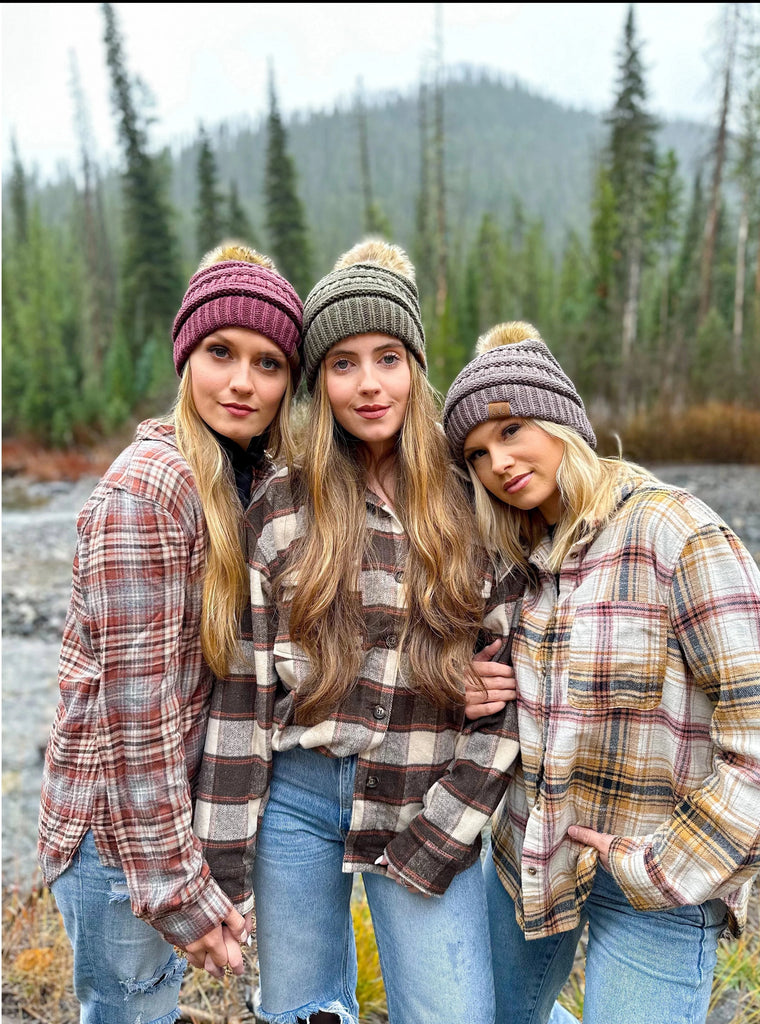 girls wearing cc beanies in front of a pond, trees, and mountains
