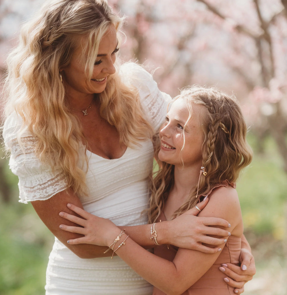 Woman and young girl embracing outdoors with a blurred natural background