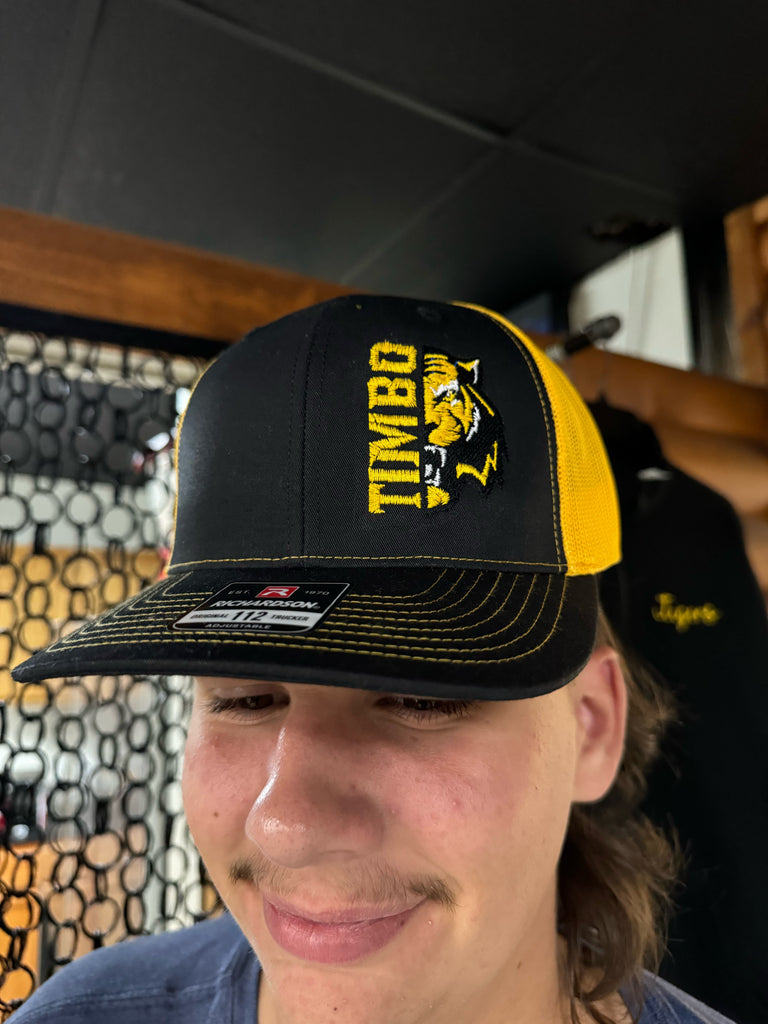 Person wearing a black and yellow cap with 'TIMBO' branding.