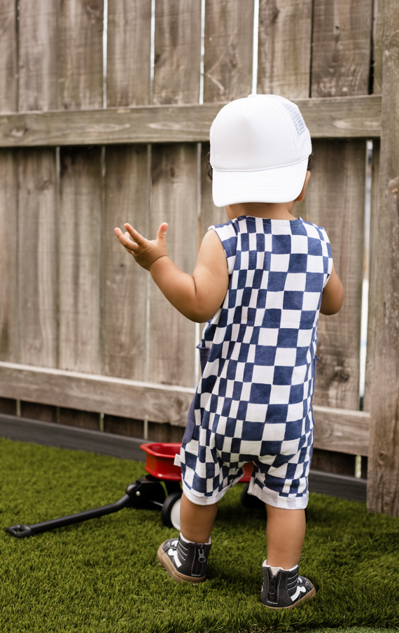 burts bee baby checked romper worn by a child in a yard with a fence