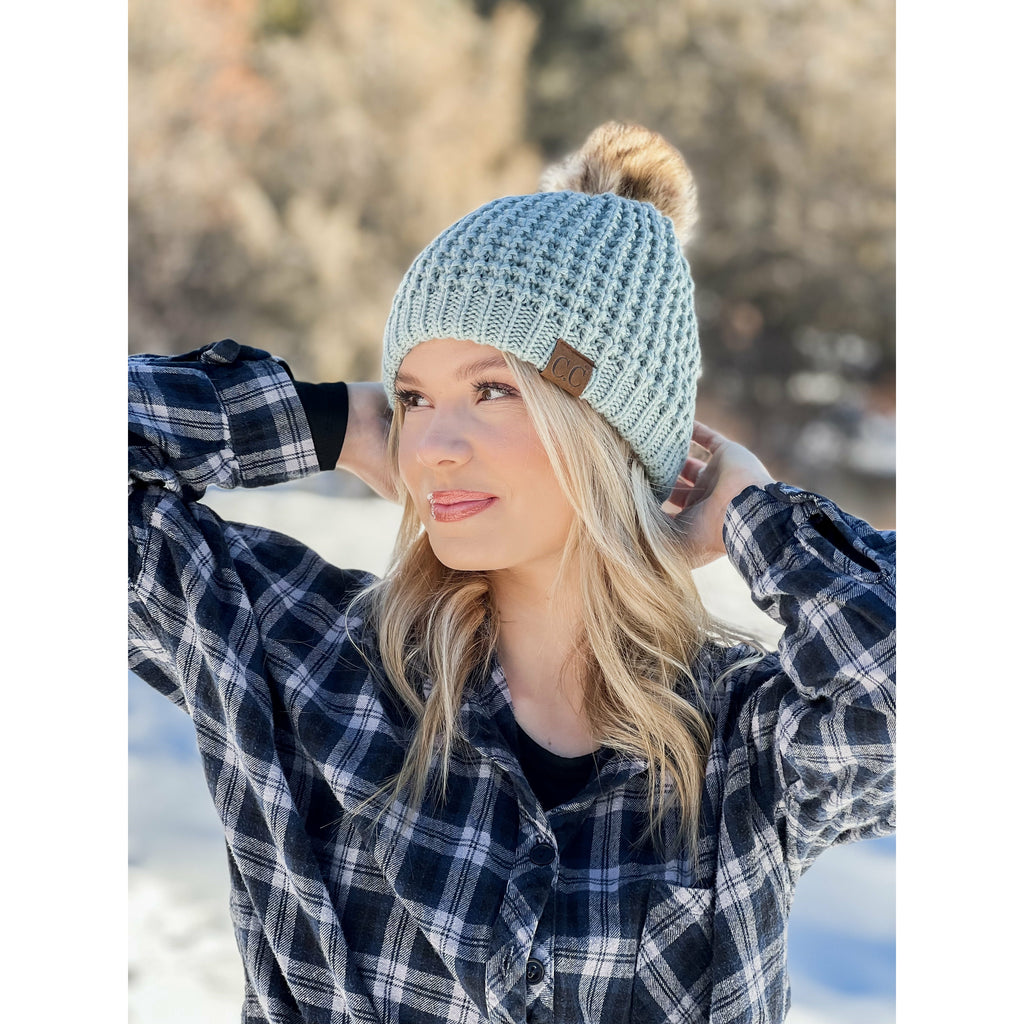 girl wearing solid waffle stitch fur pom cc beanie in the woods