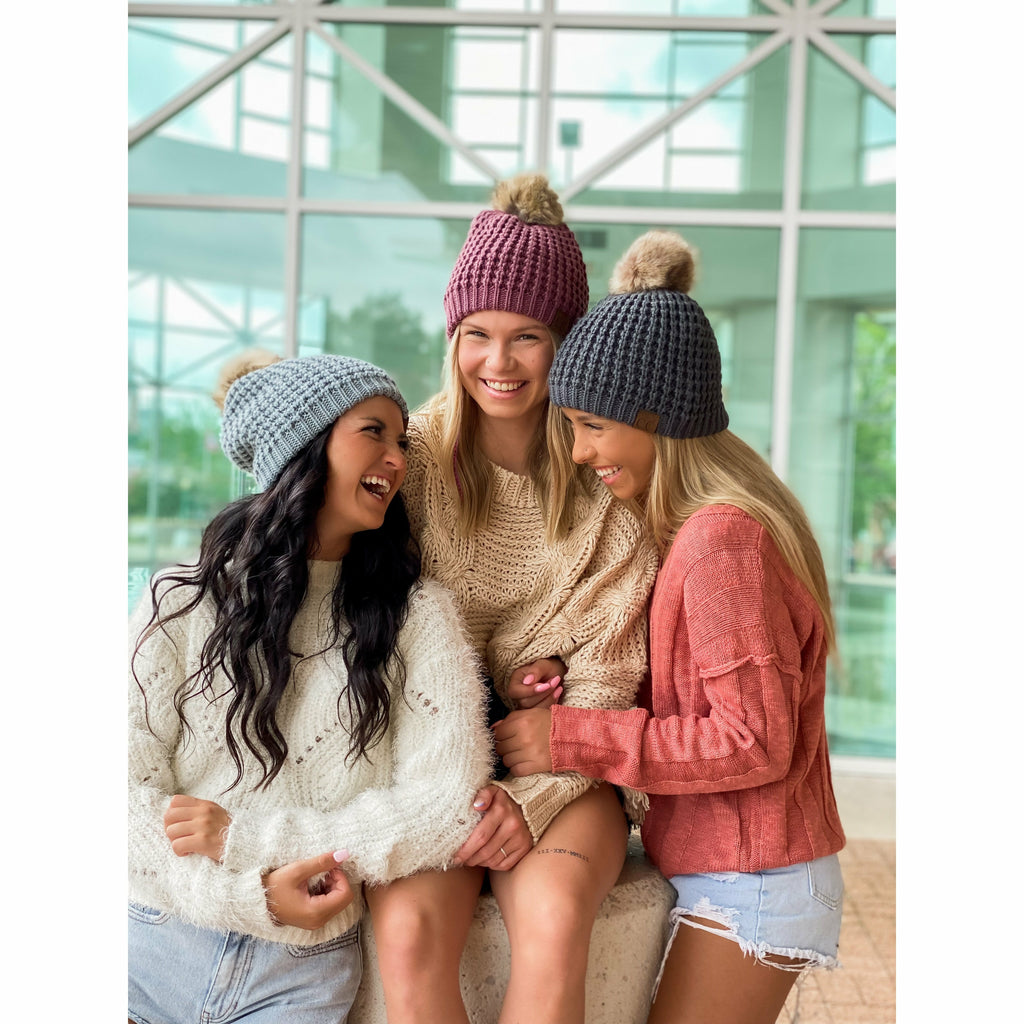 girls wearing solid waffle stitch fur pom cc beanie in front of a glass building