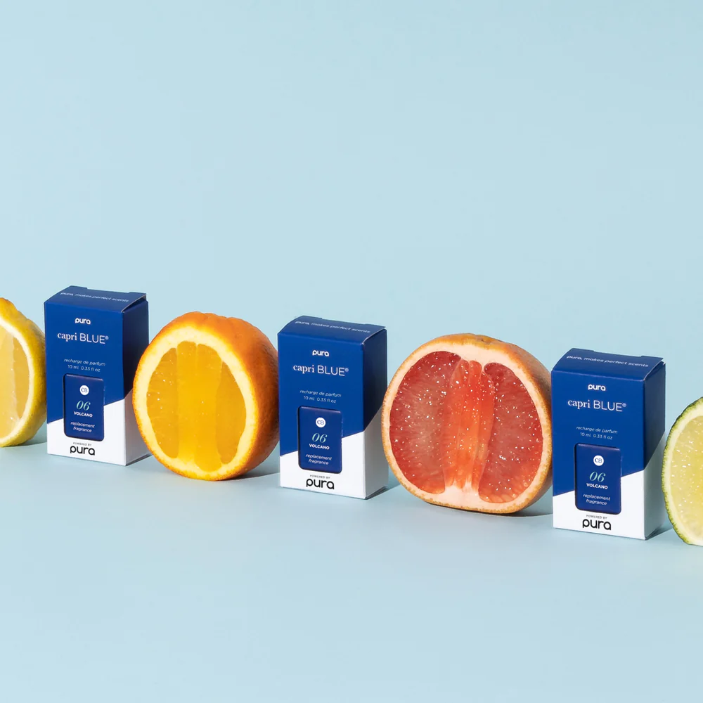 capri blue diffuser oil lined up with citrus fruit on a blue background