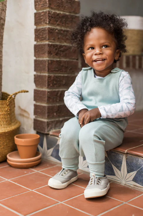 burts bee ribbed jumpsuit and tri check bodysuit set in seafoam blue on a red brick background