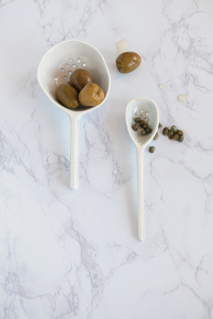 large stoneware strainer spoon on a white background