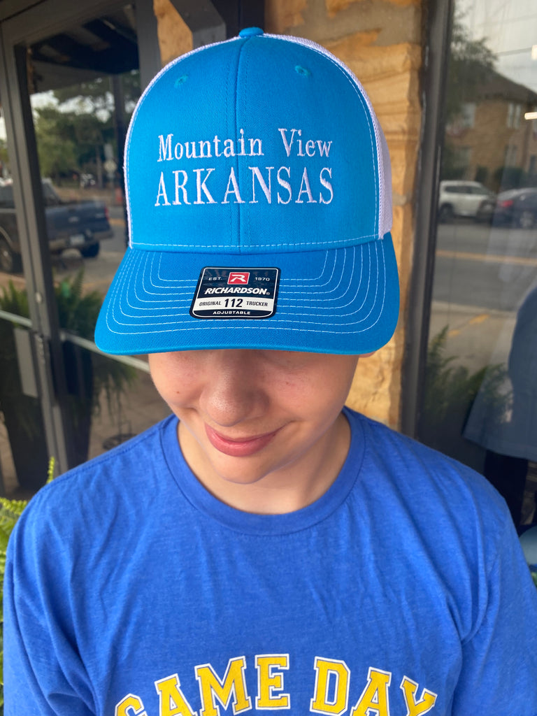 mountain view arkansas hat being worn in front of a rock building