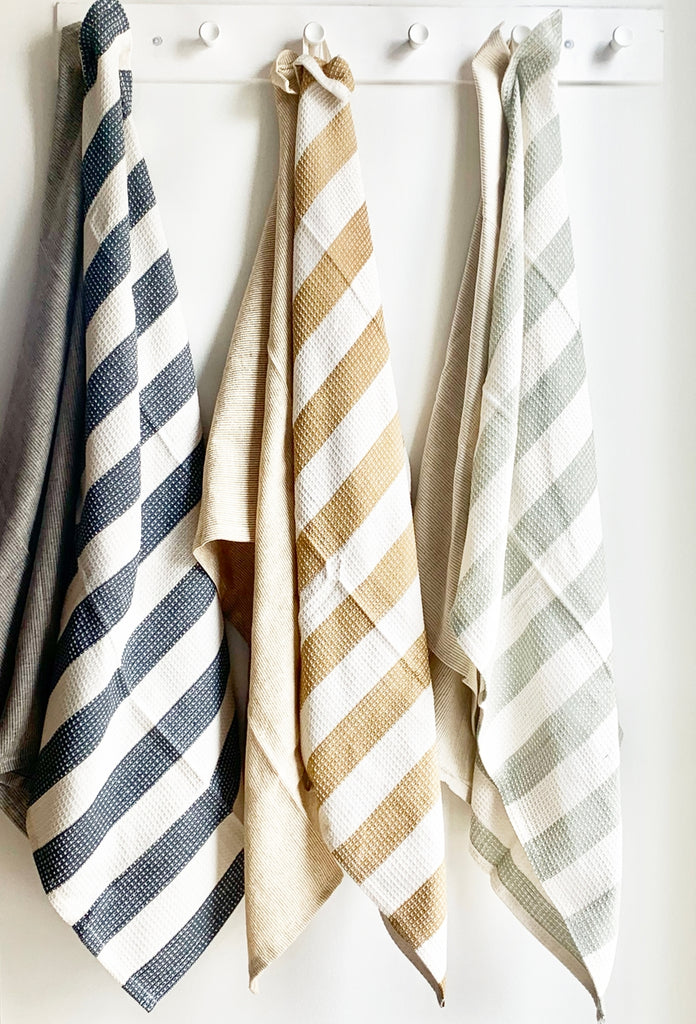 blue, yellow, and green stripped tea towels hanging on a white wall