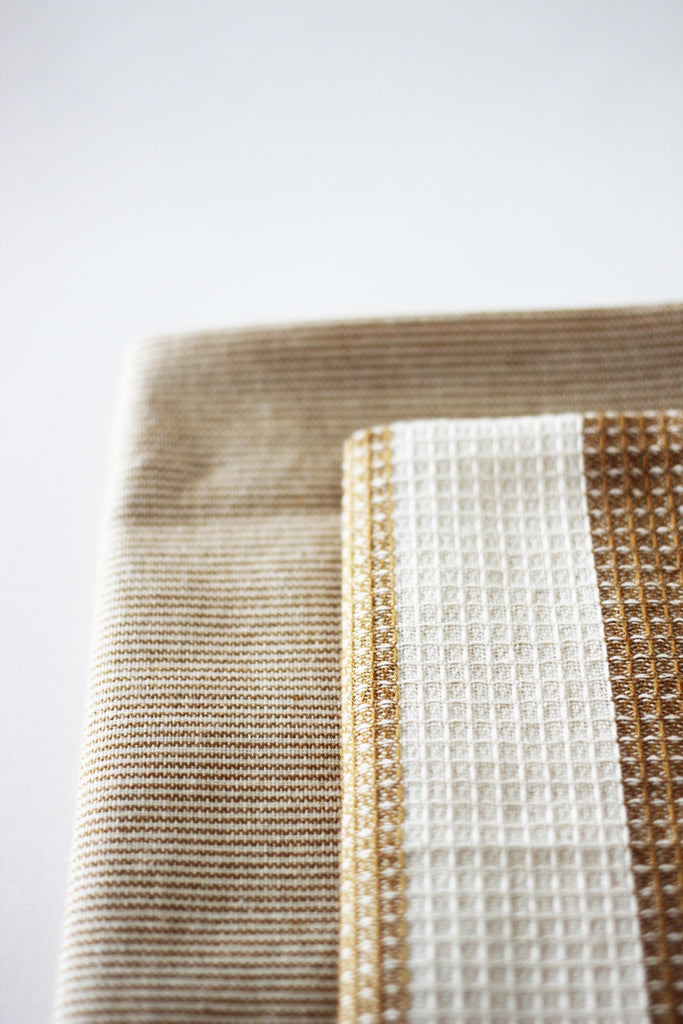 two yellow stripped tea towels on a white background