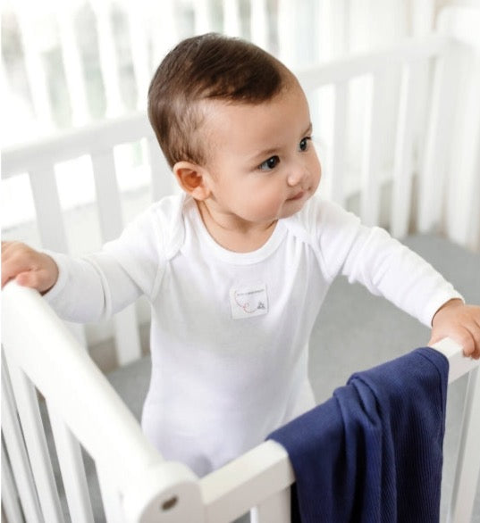 burts bee solid footie jumpsuit and knot top hat on a white background