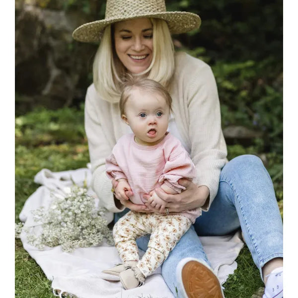 burts bee cream floral leggings and pink gauze tunic on a baby being held by a mom on a picnic 