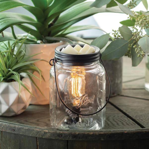 wax over mason jar warmer on a table with plants in the background