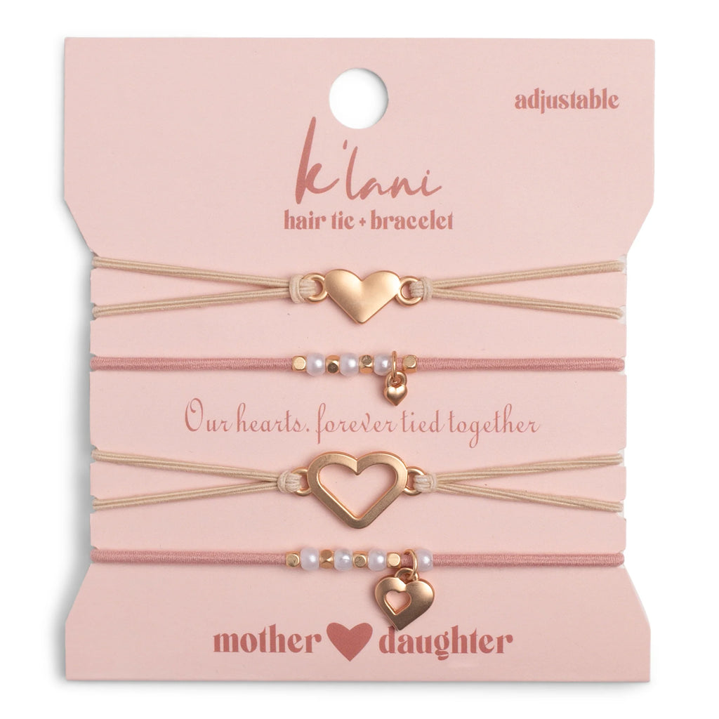 Set of heart-shaped hair tie and bracelet on a pink card with 'Kááni' branding.
