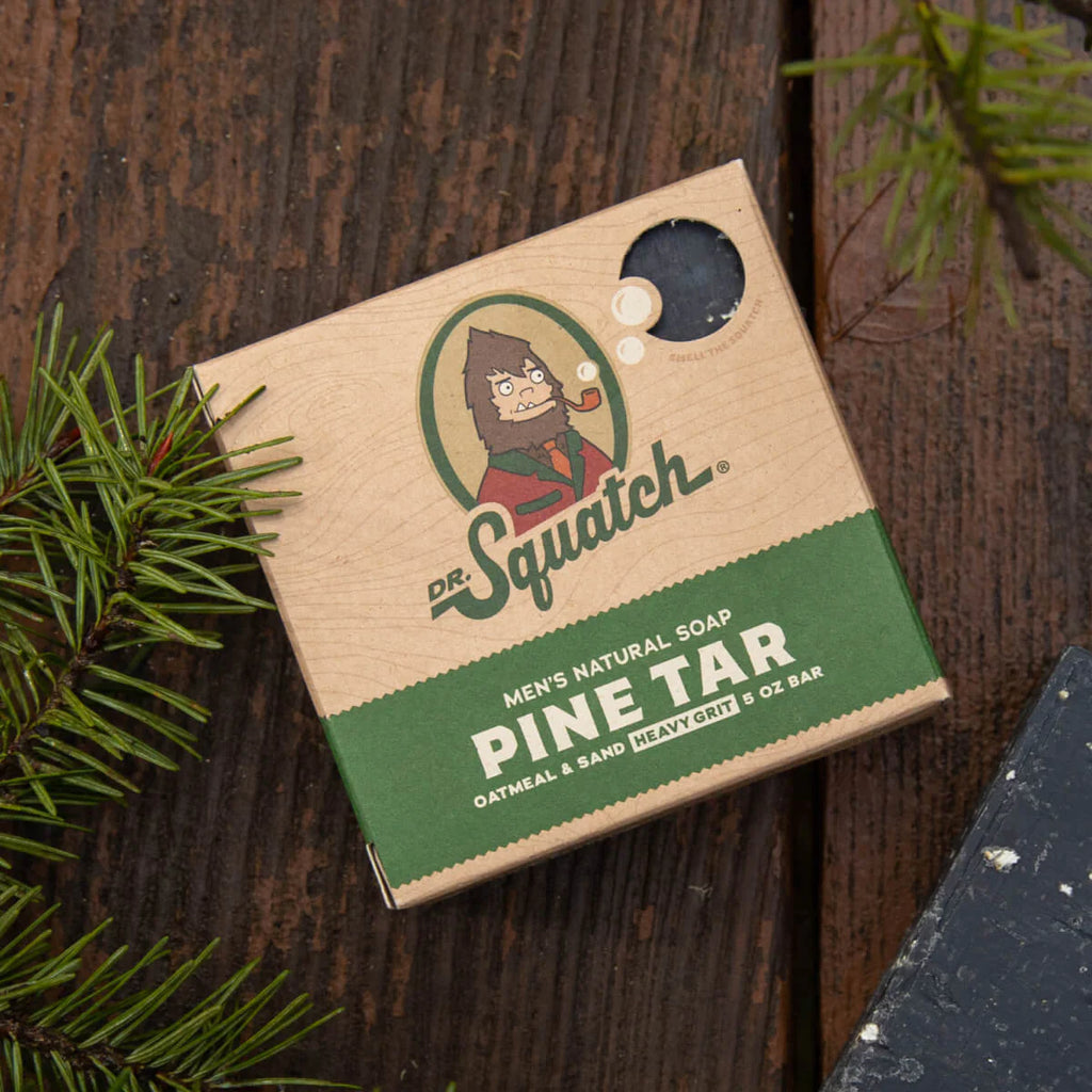 dr. squatch pine tar soap on a dark wood background with pine limbs