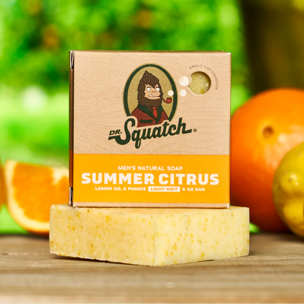 dr. squatch summer citrus soap with citrus fruits in the background sitting on a wooden table