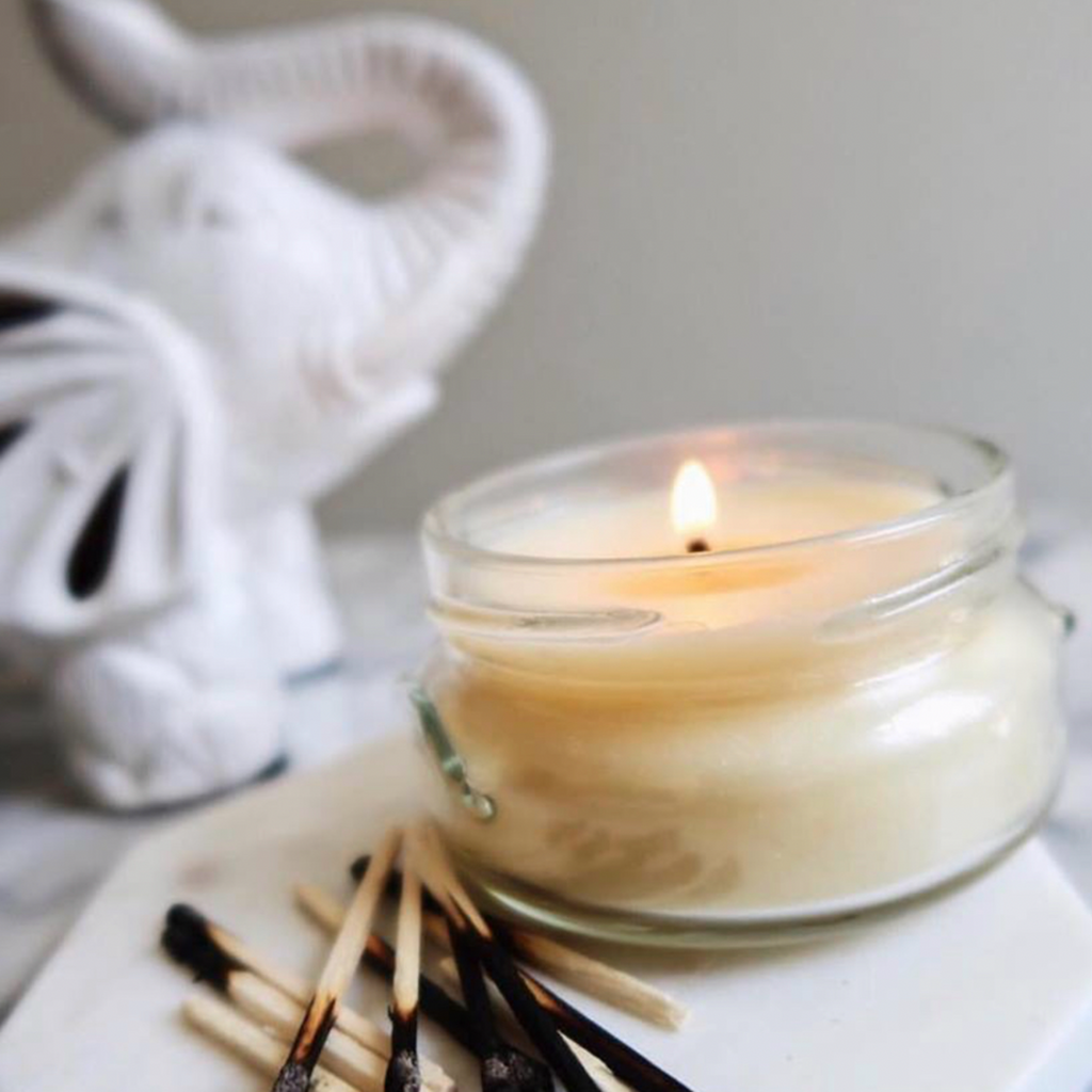 burning candle on a cream background with a white elephant